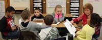 students reading to adult at writing celebration