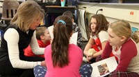 students reading to adult at writing celebration