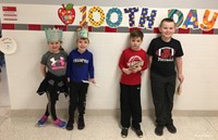 students smiling next to 100th day sign
