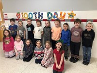 students smiling next to 100th day of school sign