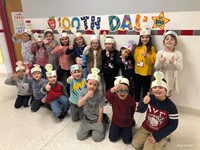 students smiling next to 100th day of school sign