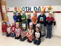 class of students smiling next to 100th day of school sign