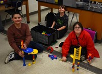 three students taking part in building activity