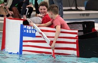 two students paddling boat back to start