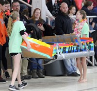 another team of students carrying boat