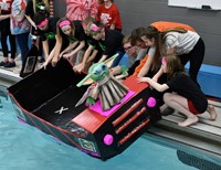 students putting boat in water
