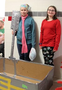 two students standing next to boat