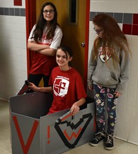 three students next to boat