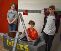 three students next to boat