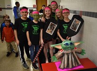 six students standing next to boat