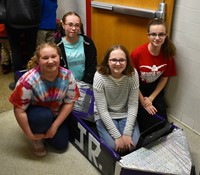 four students next to boat