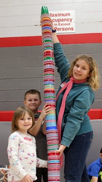 students standing next to tall stack of cups