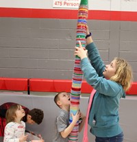 students building tall stack of cups