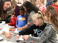 students and educator at steam night station