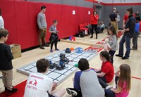 students and adults at robotics stations
