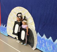 students getting picture taken next to backdrop with penguin