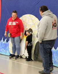 student and adults getting picture next to backdrop with penguin