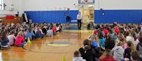 wide shot of presenter speaking at show of love assembly