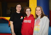 three students smiling next to bounce house