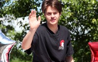 student in parade waving and smiling