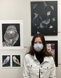 student at Emerging Artists Exhibit next to artwork