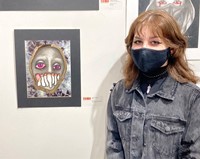 student at Emerging Artists Exhibit next to artwork