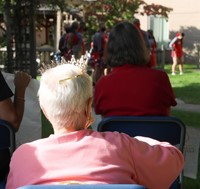 nursing home resident wearing crown watching cheerleaders perform
