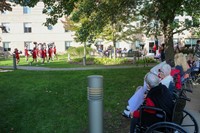 wide shot of nursing home residents watching cheerleaders perform