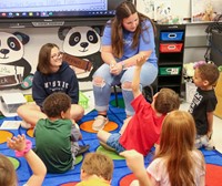 high school students reading to kindergarten students