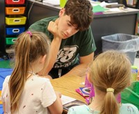 kindergarten student reading to high school student