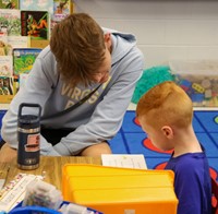 kindergarten student reading to high school student