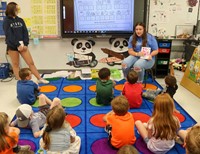 high school students reading to kindergarten students