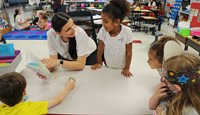 high school student reading to kindergarten students