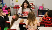 high school student reading to kindergarten students