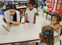 high school student reading to kindergarten students