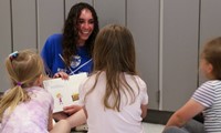 high school student reading to kindergarten students