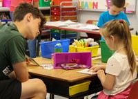 kindergarten student reading to high school student