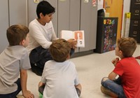 high school student reading to kindergarten students