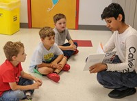 high school student reading to kindergarten students