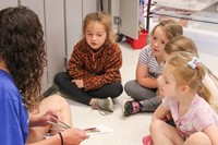 high school student reading to kindergarten students