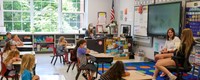 high school students reading to kindergarten students