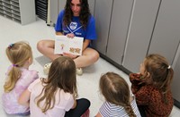 high school student reading to kindergarten students