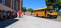 elementary students waving to seniors on buses