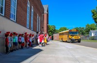elementary students waving to seniors on buses