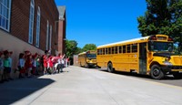 elementary students waving to seniors on buses