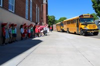 elementary students waving to seniors on buses